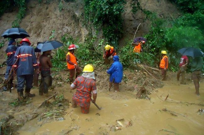 Foto: Petugas pemadam kebakaran mencari korban tanah longsor di tengah hujan deras di Bandarban, Bangladesh, Selasa (13/6). (Foto: AFP/STR)