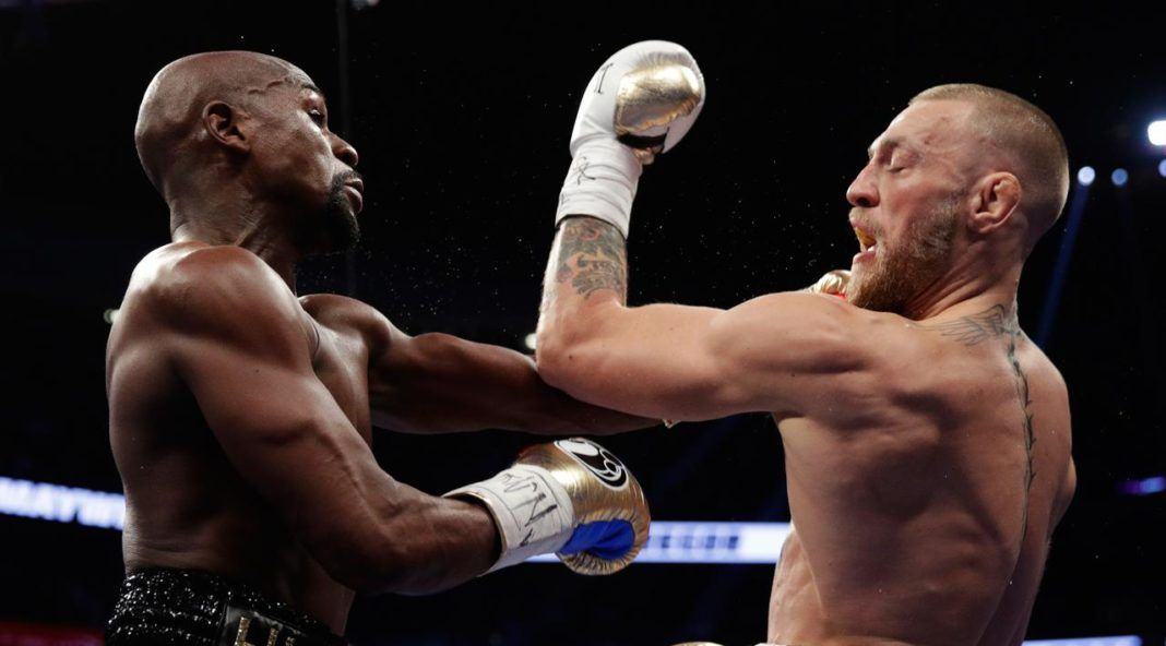 Floyd Mayweather mendaratkan pukulan diwajah Conor McGregor dalam pertandingan tinju super kelas welter di Las Vegas (26/8). Kemenangan tersebut menyempurnakan rekor Mayweather Jr di dunia tinju. (AP Photo/Isaac Brekken)