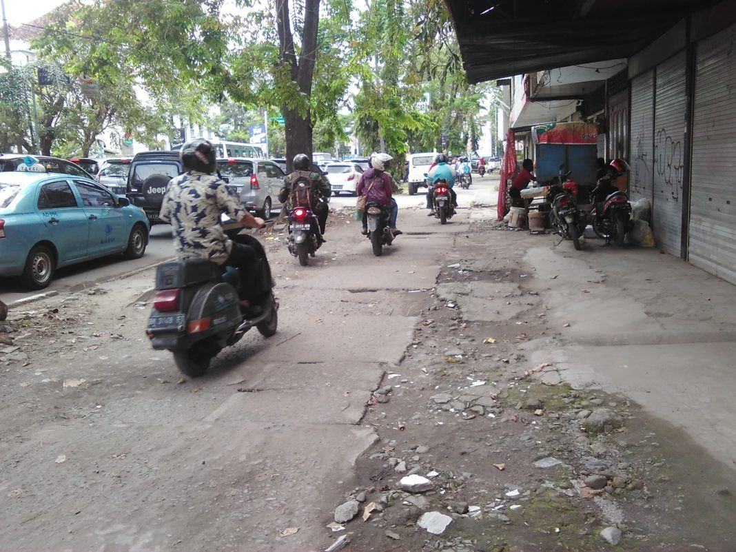 Pengendara sepeda motor melaju di trotoar untuk menghindari kemacetan jalan di kota medan