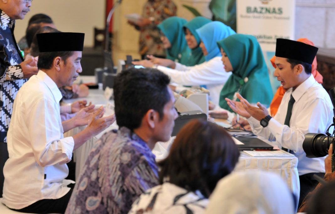 Foto: Presiden Jokowi membayar zakat kepada petugas dari BAZNAZ yang memcuka counter di Istana Negara, Jakarta, Rabu (14/6).