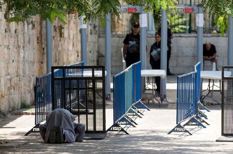 Seorang Muslim salat di depan detektor metal yang dipasang Israel di pintu masuk ke Kompleks Masjid Al-Aqsa. (Foto: EPA)