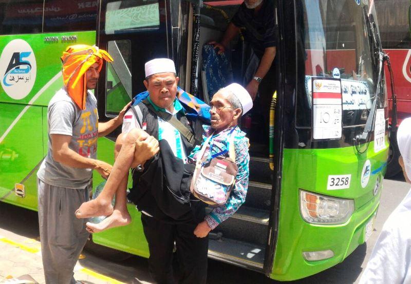 Foto: Petugas Linjam Sektor 4 Daker Madinah, Serka Alpan Arbudi menggendong Slamet bin Toryeh turun dari bus.