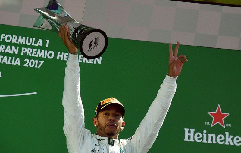 Pembalap Mercedes, Lewis Hamilton, mengangkat trofi yang diraihnya setelah menjuarai balap Formula 1 dalam Grand Prix Italia di Sirkuit Monza, Minggu, 3 September 2017. (AFP)