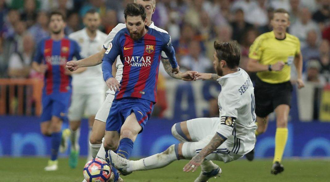 Lionel Messi mendapat adangan dari bek Real Madrid, Sergio Ramos dpada duel El Clasico di Santiago Bernabeu stadium, Madrid, Spanyol, Minggu, (23/4). Barcelona menang 3-2. (AP/Daniel Ochoa de Olza)