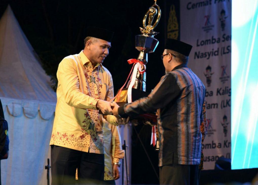 Foto: Wakil Gubernur Aceh, Nova Iriansyah menyerahkan piala juara umum kepada Kepala Kanwil Kemenag Provinsi Aceh, Daud Pakeh pada malam penutupan yang dipusatkan di Taman Sulthana Safiatudin Aceh, Jumat (13/10).
